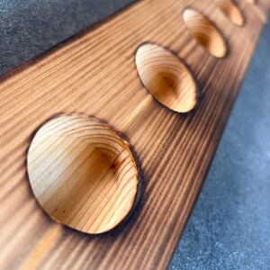 Pu&ograve; includere: Un porta bottiglie di vino in legno con sei fori rotondi per contenere bottiglie di vino. Il legno &egrave; di colore marrone chiaro e ha un aspetto rustico e usurato.