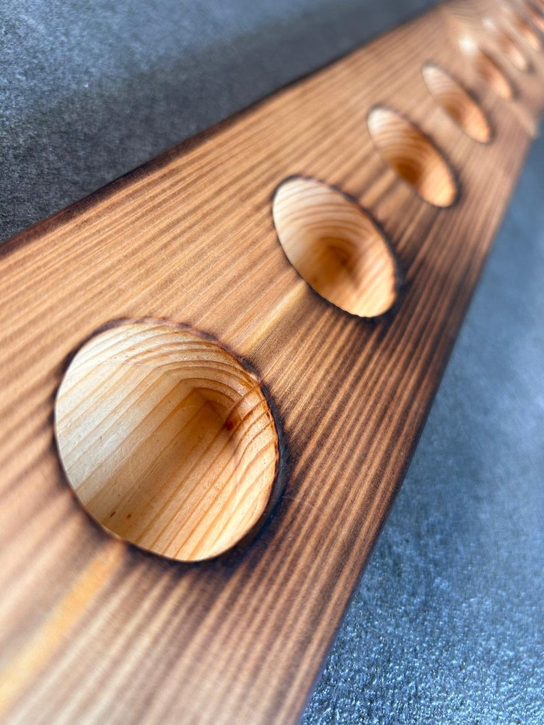 Pu&ograve; includere: Un porta bottiglie di vino in legno con sei fori rotondi per contenere bottiglie di vino. Il legno &egrave; di colore marrone chiaro e ha un aspetto rustico e usurato.