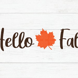 May include: A white wood background with the text "Hello Fall" in black cursive font. An orange maple leaf is centered between the words.