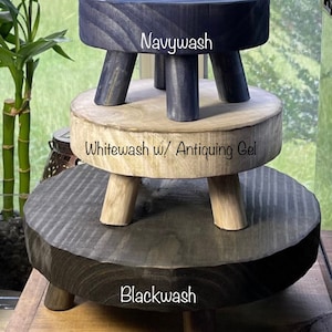 May include: Three wooden stools stacked on top of each other. The top stool is painted navy blue and labeled "Navywash". The middle stool is painted white with a light brown wash and labeled "Whitewash w/ Antiquing Gel". The bottom stool is painted black and labeled "Blackwash".