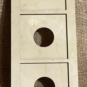 May include: A white wooden shelf unit with three circular cutouts. The shelf unit is made of plywood and has a rustic look.