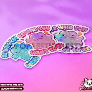 May include: Three iridescent holographic stickers with a cartoon character and the text "Be who you want to be".