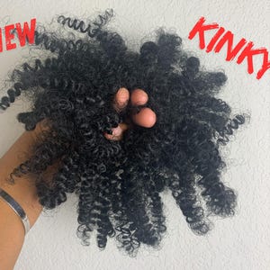 Può includere: Primo piano di un grande pacchetto di extension per capelli neri e ricci. I capelli sono molto ricci e sembrano molto spessi. Il testo "NEW" e "KINKY" è visibile nell'immagine.