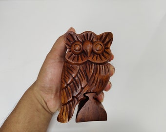 Op de afbeelding: Een houten uil puzzeldoos met ingewikkelde houtsnijwerk. De uil is bruin en heeft grote, ronde ogen. De doos is gesloten en heeft een kleine basis.