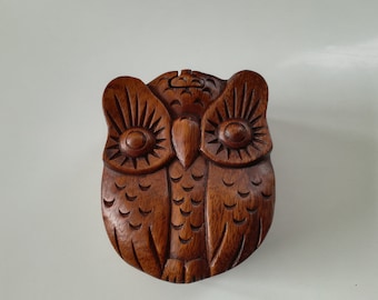 Op de afbeelding: Een houten puzzeldoos in de vorm van een uil met ingewikkelde houtsnijwerk. De ogen van de uil zijn groot en rond, en zijn veren zijn gedetailleerd.
