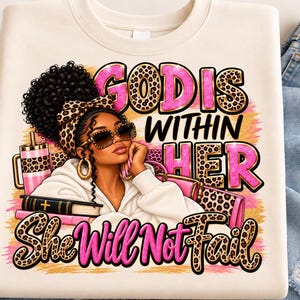 Puede incluir: Una sudadera color crema con el gráfico de una persona de cabello oscuro rizado, con diadema y gafas de sol de estampado de leopardo. El texto "GOD IS WITHIN HER She Will Not Fail" aparece en letras rosas y de leopardo junto a un libro.