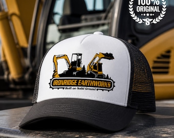 May include: A white and black trucker hat featuring a graphic of two yellow excavators and the text "IRONRIDGE EARTHWORKS Built on Solid Ground" in black and yellow lettering on the front panel, with a black mesh back and a black brim.