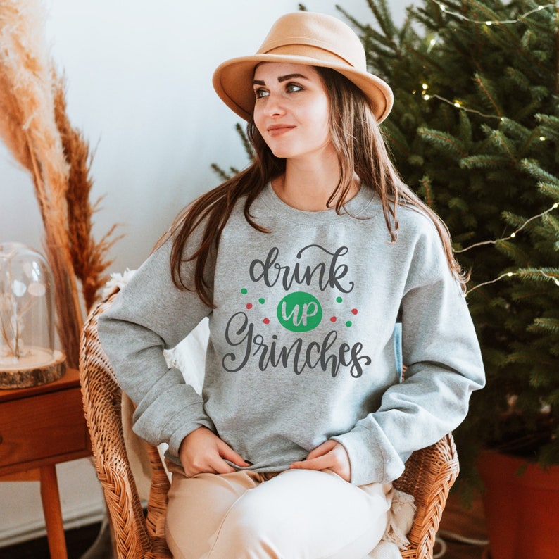 May include: A gray sweatshirt with the text "drink up Grinches" in green and red lettering. The sweatshirt is decorated with small green and red dots.