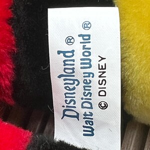 May include: White tag with black text that reads "Disneyland&reg; Walt Disney World&reg; &copy; DISNEY".