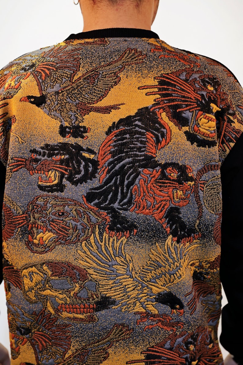 May include: A black sweater featuring a colourful pattern of tigers, birds, and skulls. The design is woven into the fabric and has a vintage feel.