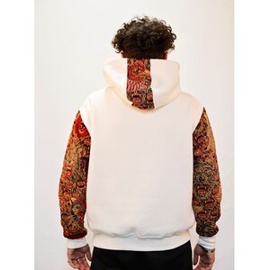 May include: White hooded sweatshirt with a red and gold patterned design on the back and sleeves. The pattern features a repeated image of a lion's head.