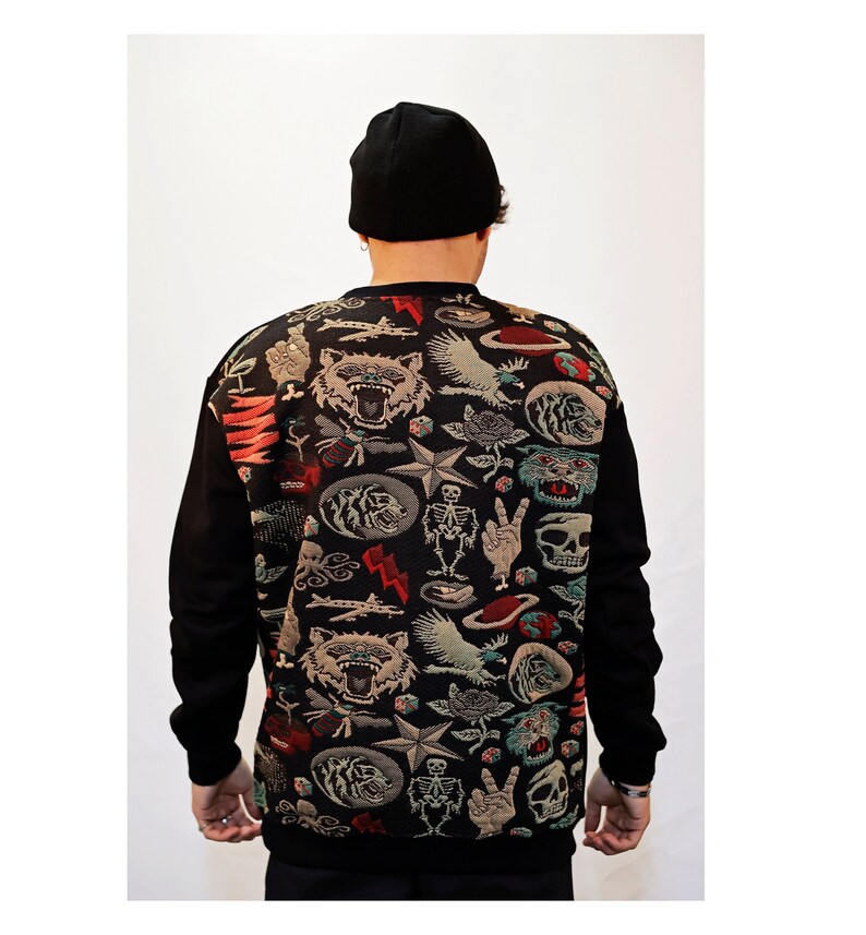 Puede incluir: Sudadera negra con un estampado colorido de varios s&iacute;mbolos, incluyendo calaveras, estrellas y animales. El estampado es de estilo vintage.