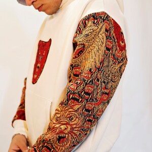 May include: A white hoodie with a red bear graphic on the front and a multi-colored wolf graphic on the sleeve.