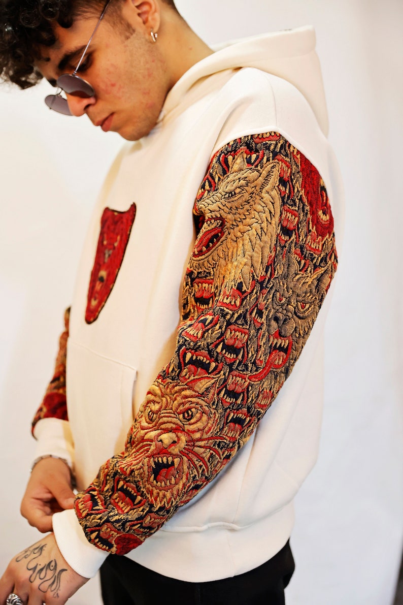 May include: A white hoodie with a red bear graphic on the front and a multi-colored wolf graphic on the sleeve.