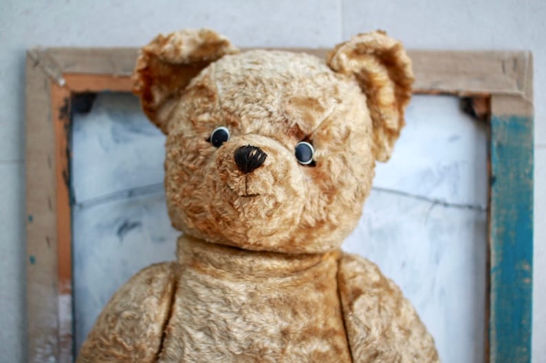 Peut inclure: Un ours en peluche vintage avec un pelage us&eacute; de couleur fauve et des yeux en boutons noirs. L'ours a un nez cousu et une expression douce, l&eacute;g&egrave;rement triste.