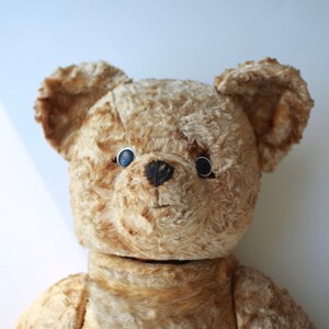 Peut inclure: Un ours en peluche vintage &agrave; la fourrure brune et aux yeux noirs en boutons. L'ours a un aspect us&eacute; et d&eacute;lav&eacute;, ce qui sugg&egrave;re qu'il est antique.