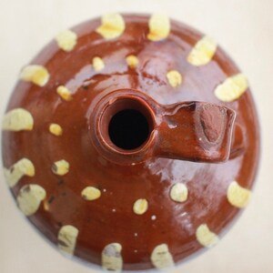 K&ouml;nnte beinhalten: Eine braune Keramikkanne mit wei&szlig;em &Uuml;berzug und einem Henkel. Die Kanne hat einen runden K&ouml;rper und eine breite &Ouml;ffnung oben. Der &Uuml;berzug ist ungleichm&auml;&szlig;ig, wodurch ein marmorierter Effekt entsteht.