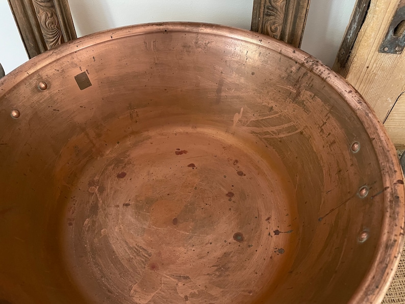 Puede incluir: Una olla grande de cobre con una p&aacute;tina desgastada y envejecida. El interior de la olla es liso y muestra signos de uso. La olla tiene una abertura redonda ancha y un borde ligeramente acampanado.