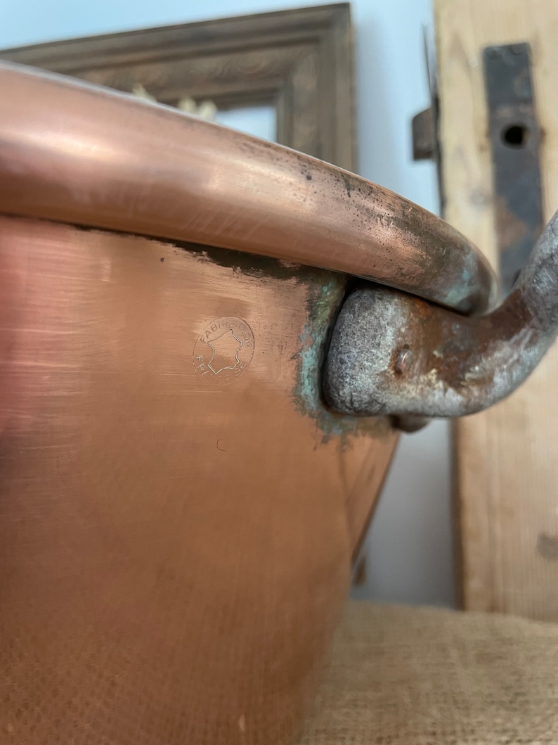 Puede incluir: Una olla grande de cobre con asa y una marca del fabricante que dice "FABRIQUE EN FRANCE".