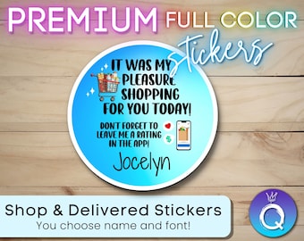 Puede incluir: Una pegatina redonda azul y blanca con el texto "It was my pleasure shopping for you today! Don't forget to leave me a rating in the app! Jocelyn" y un carrito de compras de dibujos animados con comestibles. La pegatina está sobre un fondo de madera.