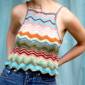 May include: A colorful crocheted tank top with a wavy pattern in shades of blue, green, orange, pink, and red. The top has a halter neckline and thin straps.
