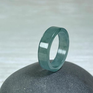 May include: A jade ring with a smooth, polished surface. The ring is a light green color and has a simple, elegant design.