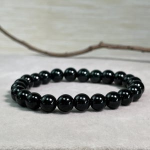 以下が含まれることがあります： 丸くて滑らかな黒いビーズで作られた黒いブレスレット。ブレスレットは天然のブラックオニキスで作られています。