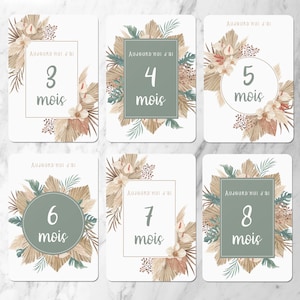 May include: Eight printable cards with a boho theme. Each card has a different number from 3 to 8 with the words 'Aujourd'hui j'ai' and 'mois' (meaning 'Today I am' and 'months' in French). The cards feature a neutral color palette with beige, brown, and green tones. The cards are decorated with palm leaves, dried flowers, and other natural elements.