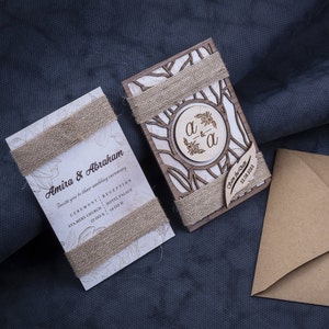 Pode incluir: Um conjunto de convites de casamento com um tema r&uacute;stico. O cart&atilde;o de convite apresenta um design floral e o texto "Amira & Abraham". O segundo cart&atilde;o &eacute; feito de madeira com um design de corte a laser e o texto "Save the Date 22.08.2022".