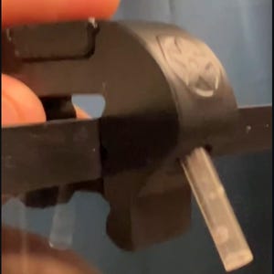 Puede incluir: Herramienta negra de gestión de tubos con un tubo transparente insertado. La herramienta tiene el texto "CLEV.CA Tubing Management" en blanco. La herramienta está sujeta por una persona.