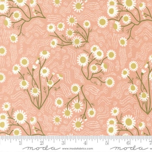 May include: A fabric with a repeating pattern of white daisies with yellow centers and green stems on a peach background. The fabric also features a subtle, textured, white, wavy pattern. The fabric is marked with a ruler in inches.
