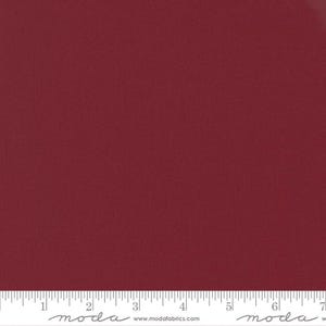 May include: A solid burgundy fabric swatch with a subtle texture. The fabric is measured with a ruler in inches.