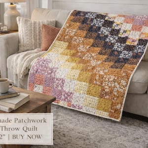 May include: Handmade patchwork lap and throw quilt, 45"x62", draped over a beige sofa. The quilt features a geometric pattern in shades of yellow, orange, brown, and purple. A coffee table with books and a mug is in the foreground.