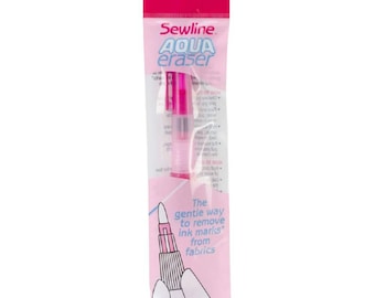 May include: A pink Sewline Aqua Eraser in a plastic package. The eraser is designed to remove ink marks from fabrics. The package has the text "The gentle way to remove ink marks from fabrics".