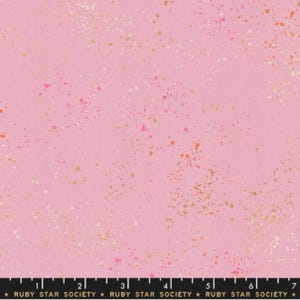 May include: Pink fabric with a speckled pattern of gold, white, and pink dots. The fabric is from Ruby Star Society.