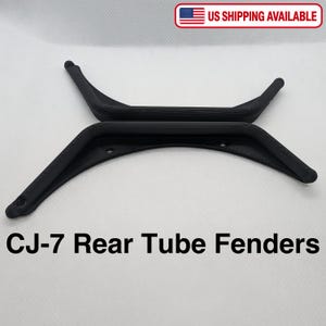 Puede incluir: Dos guardabarros traseros tubulares negros CJ-7 con acabado texturizado. Cada guardabarros presenta un dise&ntilde;o curvo con orificios de montaje integrados en los extremos y a lo largo del borde interior. El texto CJ-7 Rear Tube Fenders aparece debajo.