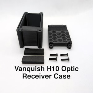 Pode incluir: Caixa de plástico preta com um padrão de favo de mel na parte superior, duas almofadas de espuma e quatro parafusos. A caixa está etiquetada "Vanquish H10 Optic Receiver Case".