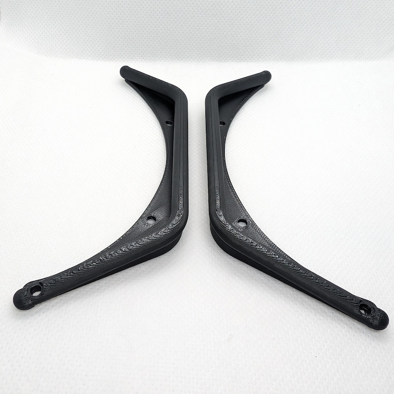 Puede incluir: Un par de soportes en L negros impresos en 3D con un dise&ntilde;o curvo. Cada soporte tiene un acabado de superficie texturizado e incluye dos orificios de montaje circulares colocados a lo largo del marco para una fijaci&oacute;n segura.