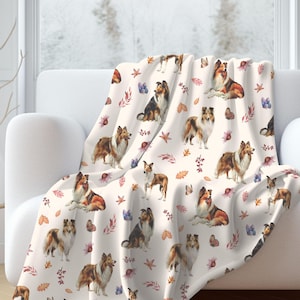 May include: A white throw blanket with a repeating pattern of brown and white dogs, autumn leaves, and butterflies.