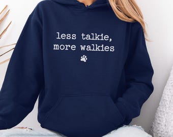 May include: Navy blue hoodie with the text "less talkie, more walkies" and a paw print graphic. The hooded sweatshirt has a front pocket and a drawstring hood. The word "Navy" is written in cursive at the bottom.