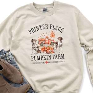 May include: A beige sweatshirt with the text "POINTER PLACE PUMPKIN FARM" and a graphic of a red truck with pumpkins and two dogs. The text below the graphic says "U-PICK PUMPKINS FRESH PRESSED CIDER".