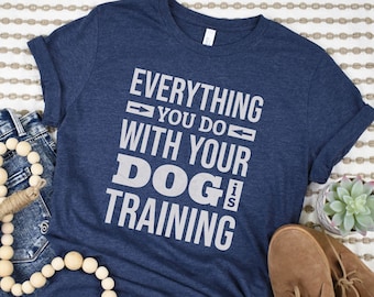 May include: A navy blue t-shirt with white text that reads "Everything you do with your dog is training".