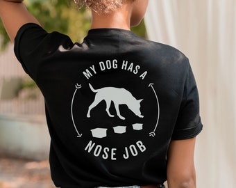 May include: Black t-shirt with a white graphic of a dog sniffing three bowls with the text "My dog has a nose job".