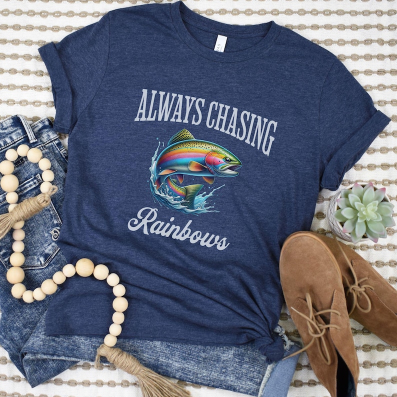 May include: A navy blue t-shirt with a rainbow trout graphic and the text "Always Chasing Rainbows".