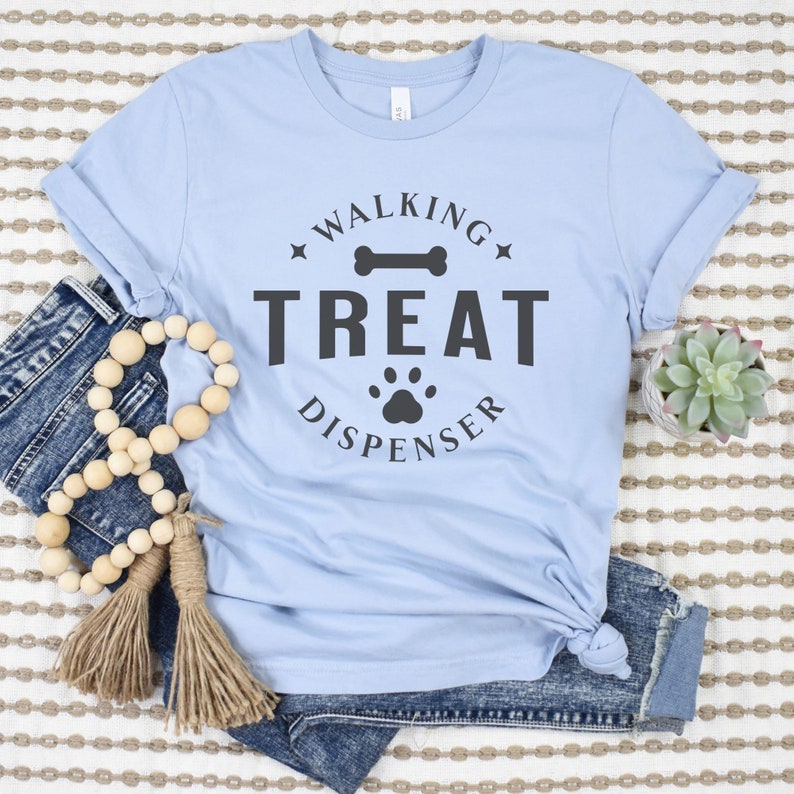 May include: A light blue t-shirt with a black graphic that says "Walking Treat Dispenser" with a bone and paw print.