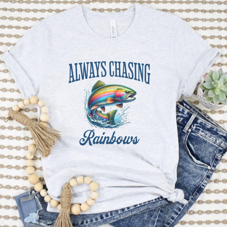 May include: A gray t-shirt with the text "Always Chasing Rainbows" and a colorful rainbow trout jumping out of the water.