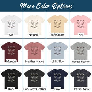 May include: A chart displaying various colour options for a t-shirt featuring the text "ROUX the day" and a graphic of a whisk and a bowl. The colours include Ash, Natural, Soft Cream, Pink, Maroon, Heather Mauve, Light Blue, Athletic Heather, Black, Dark Grey Heather, Navy, and Heather Navy.