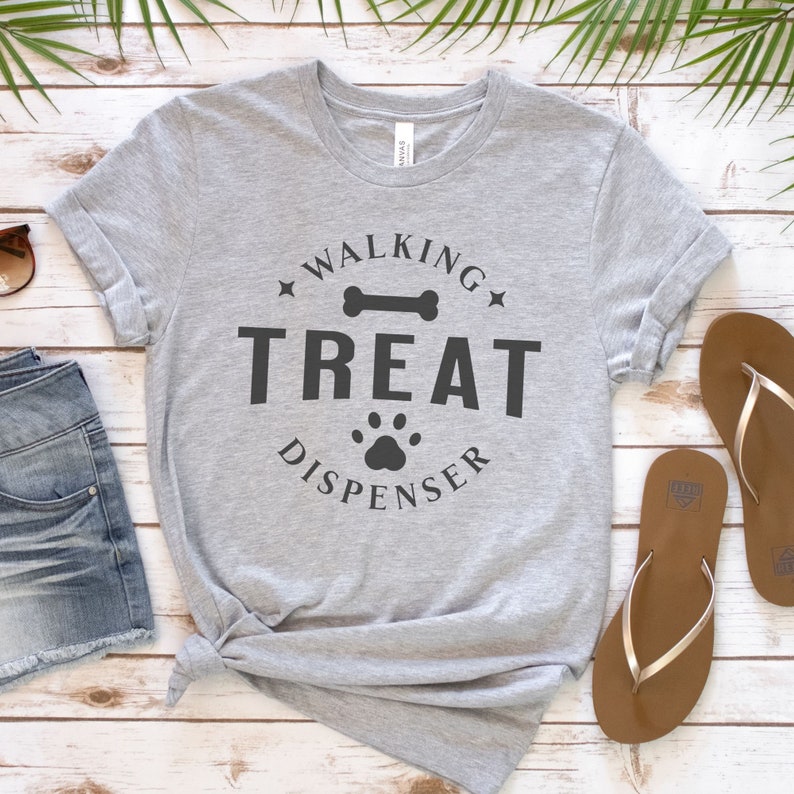 May include: Gray t-shirt with the text "Walking Treat Dispenser" in black lettering. The text is surrounded by a circle with a bone and paw print.