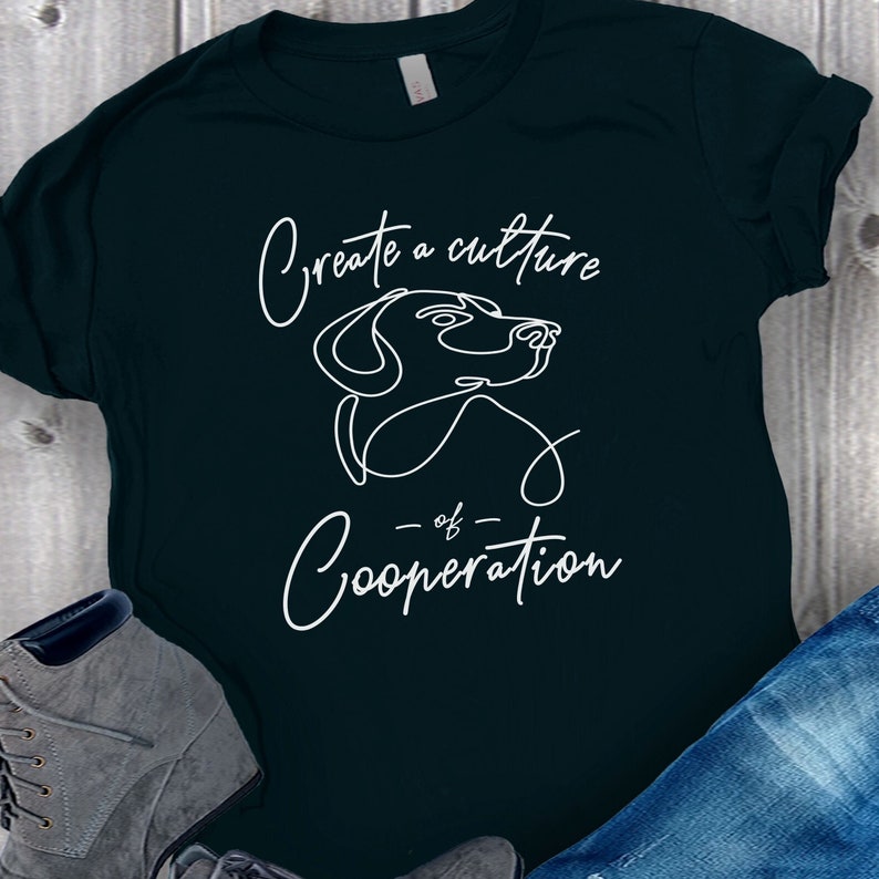 May include: A dark green t-shirt with a white outline of a dog's head and the text "Create a culture of Cooperation".