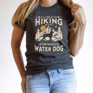 Hiking With My Portuguese Water Dog T-Shirt. A classic mountain design with Portuguese Water Dog silhouette, made for the Portie mom or dad who loves hiking with their dog. A great Portuguese Water Dog lover gift idea!